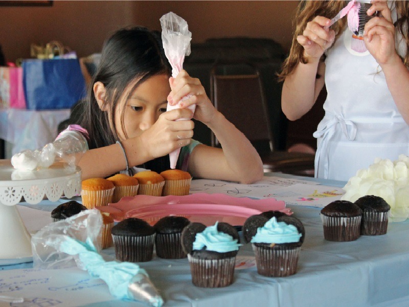 Kid putting frosting in the cupcakes