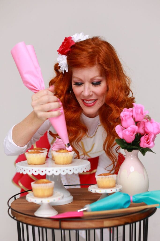 A person putting an icing on the cupcake