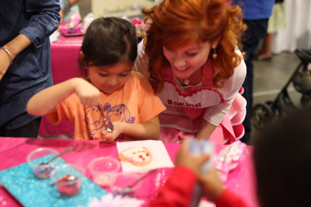 Melissa teaching a little girl on how to bake